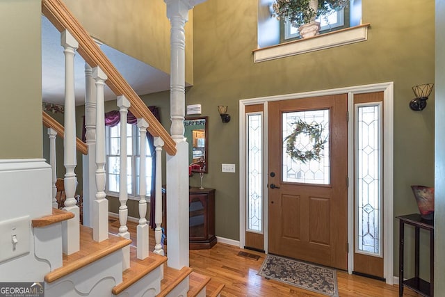 entrance foyer featuring plenty of natural light, a towering ceiling, and light hardwood / wood-style flooring