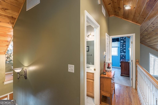 hall with vaulted ceiling, wood ceiling, light wood-type flooring, and sink