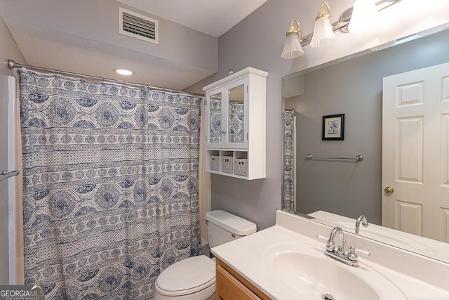 bathroom featuring toilet, a textured ceiling, walk in shower, and vanity