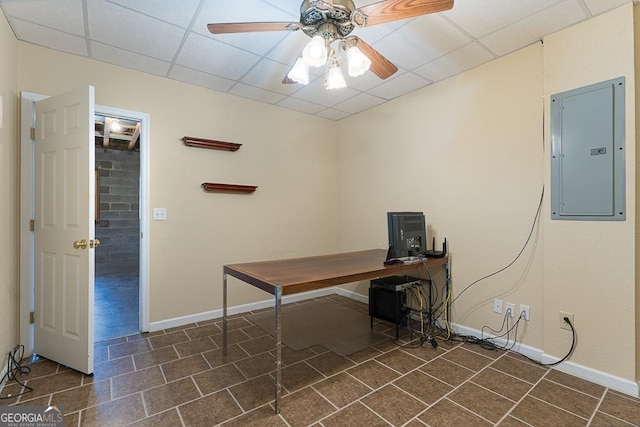 unfurnished office with ceiling fan, electric panel, and a drop ceiling