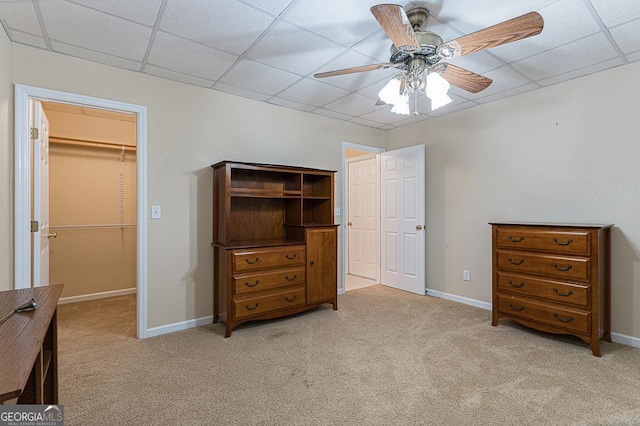 bedroom featuring ceiling fan, a paneled ceiling, light carpet, a walk in closet, and a closet