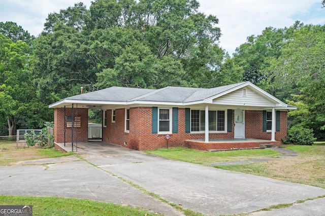 ranch-style house featuring a front yard, covered porch, and a carport