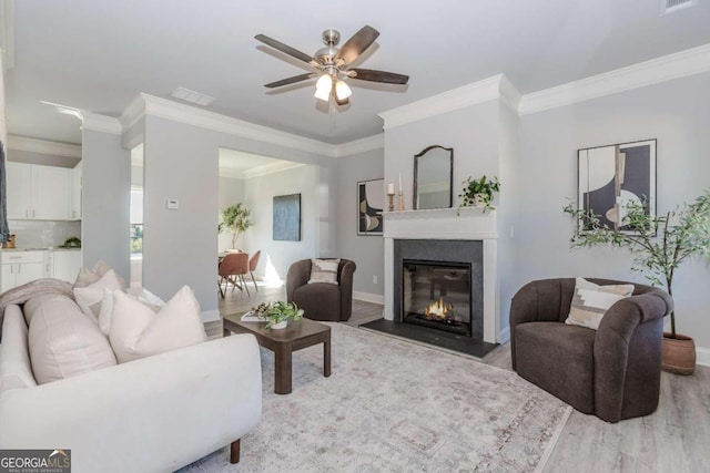 living room with ornamental molding, light hardwood / wood-style floors, and ceiling fan