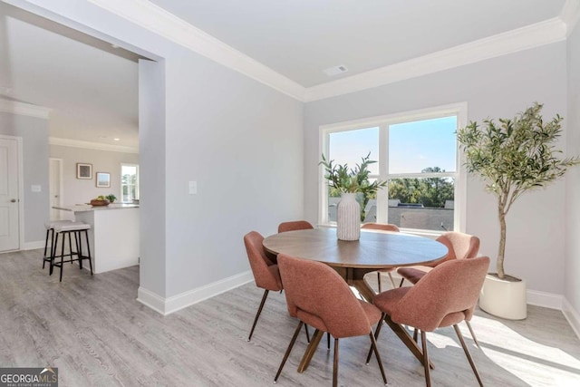 dining room featuring light hardwood / wood-style flooring, ornamental molding, and a healthy amount of sunlight