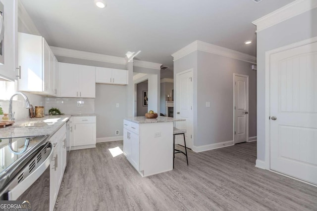 kitchen with a center island, a kitchen bar, light hardwood / wood-style flooring, and white cabinetry