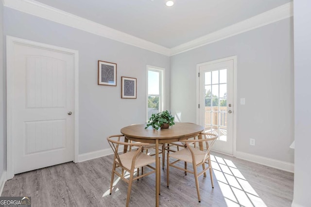 dining space featuring ornamental molding and light hardwood / wood-style flooring