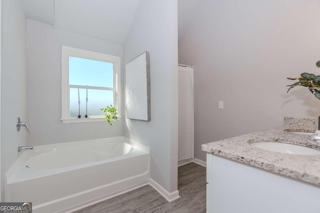 bathroom with vanity, a tub, wood-type flooring, and vaulted ceiling