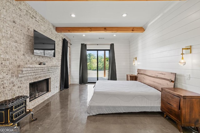 bedroom with a brick fireplace, access to exterior, and beam ceiling