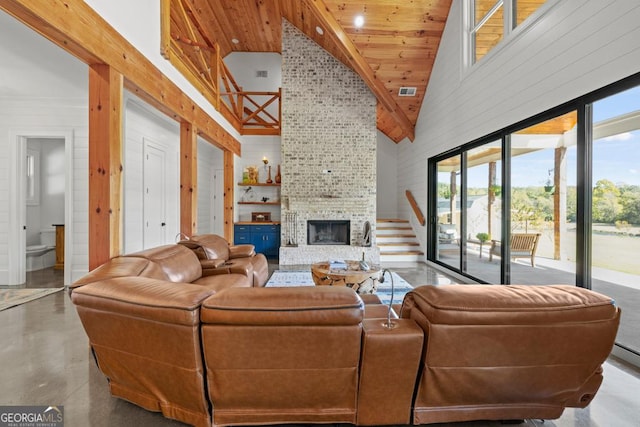 living room with a large fireplace, concrete floors, and high vaulted ceiling