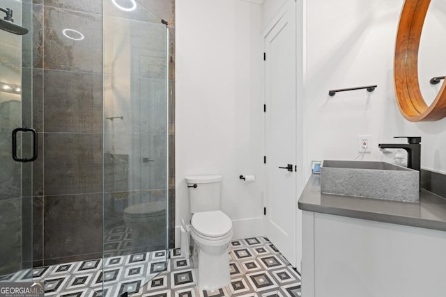 bathroom featuring a shower with door, vanity, and toilet