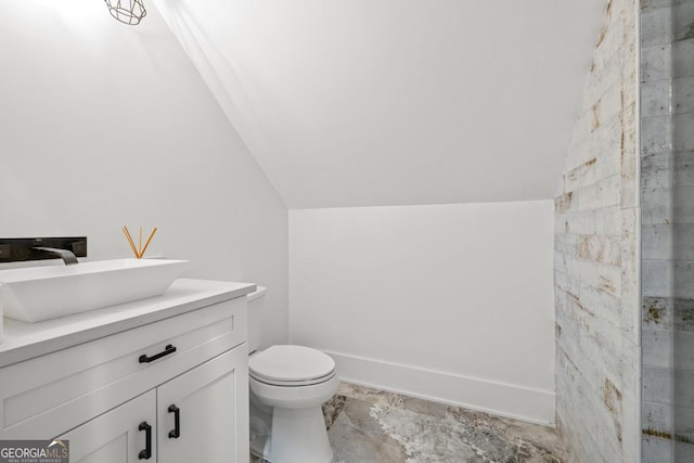 bathroom featuring lofted ceiling, toilet, and vanity