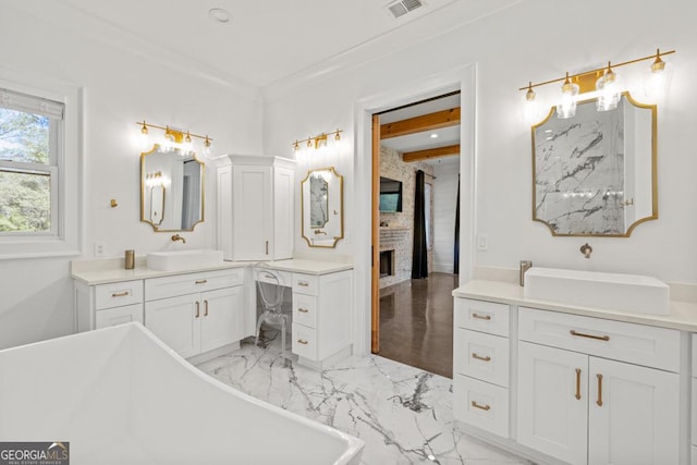 bathroom with a tub to relax in, a fireplace, beam ceiling, and vanity