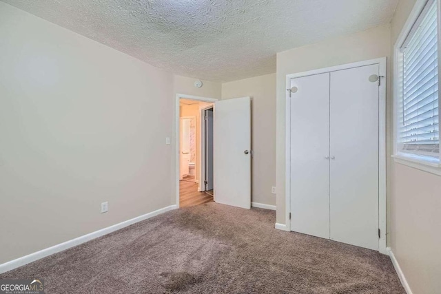 unfurnished bedroom featuring a closet, light carpet, and a textured ceiling