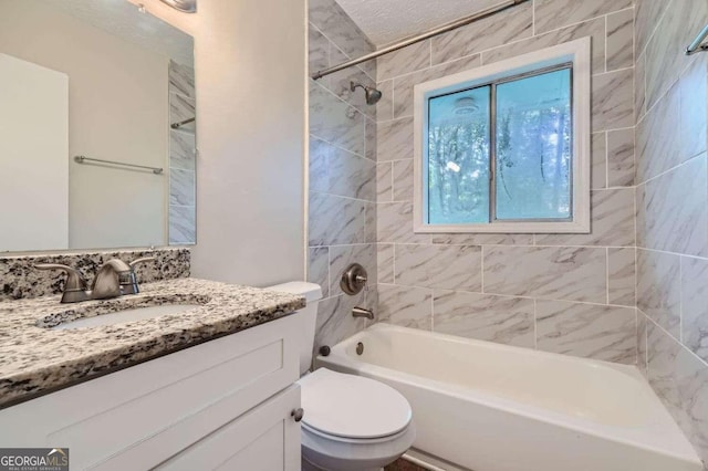 full bathroom featuring vanity, toilet, a textured ceiling, and tiled shower / bath