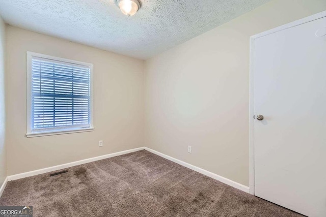 carpeted empty room with a textured ceiling