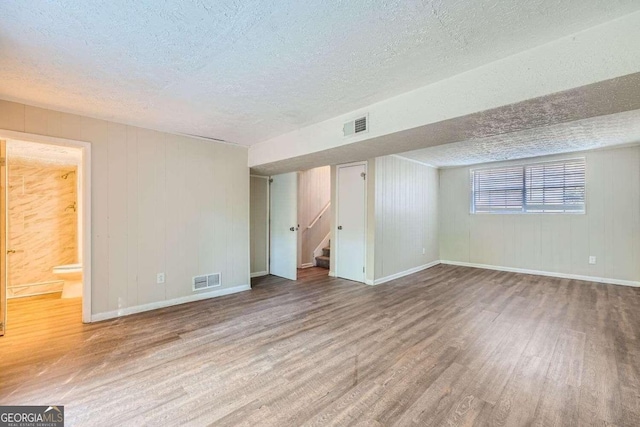 interior space with hardwood / wood-style flooring, a textured ceiling, and wooden walls