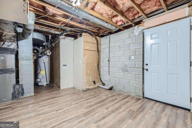 basement with hardwood / wood-style floors and water heater