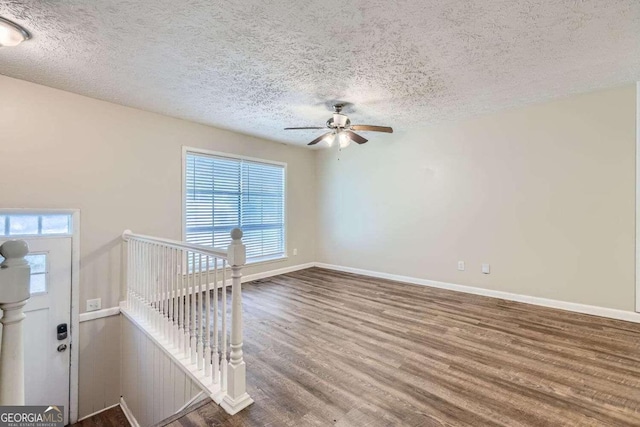 empty room with a wealth of natural light, hardwood / wood-style floors, and a textured ceiling