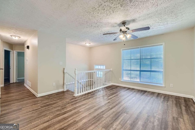 spare room with ceiling fan, a textured ceiling, and dark hardwood / wood-style flooring