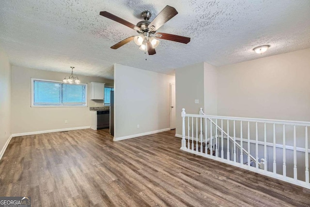 spare room featuring a textured ceiling, wood-type flooring, and ceiling fan with notable chandelier