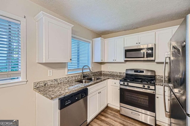 4660 Edwina Ln SW, Atlanta, GA 30331 - kitchen with stainless steel appliances, a sink, white cabinets, dark stone counters, and a textured ceiling