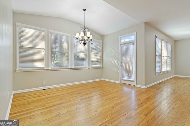 unfurnished dining area with light hardwood / wood-style flooring, a notable chandelier, and lofted ceiling