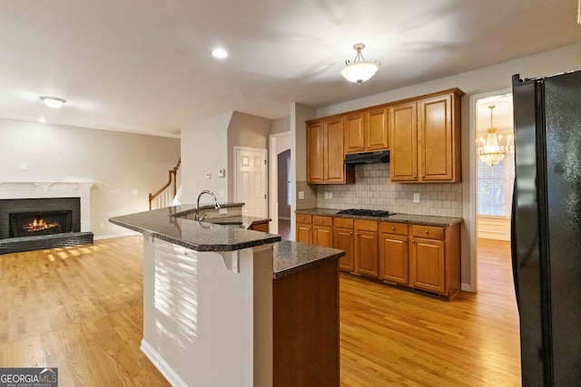 kitchen with sink, backsplash, black fridge, light hardwood / wood-style floors, and a breakfast bar