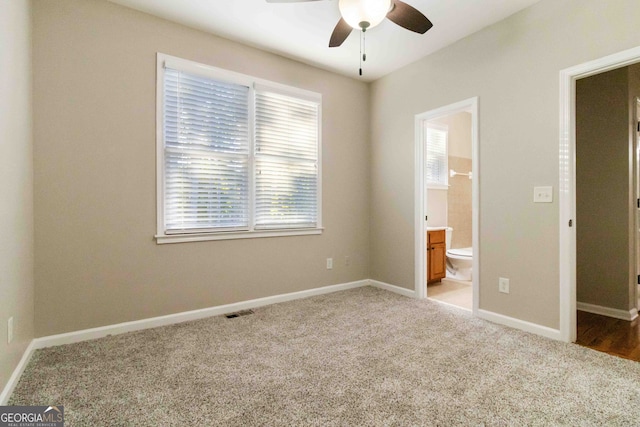 unfurnished bedroom featuring ceiling fan, light colored carpet, and ensuite bath