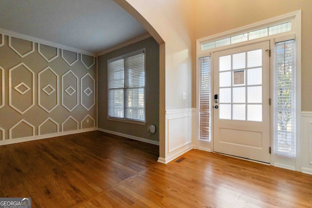 entryway featuring crown molding, wood-type flooring, and a healthy amount of sunlight