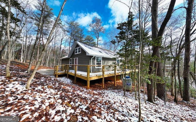 snow covered back of property with a wooden deck