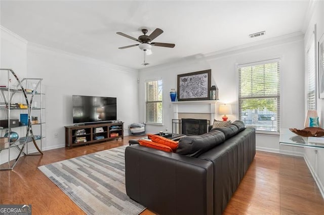 living room featuring light hardwood / wood-style floors, crown molding, ceiling fan, and a wealth of natural light