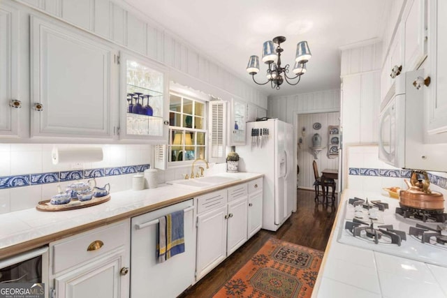 kitchen featuring dark wood-type flooring, sink, a notable chandelier, white cabinetry, and white appliances