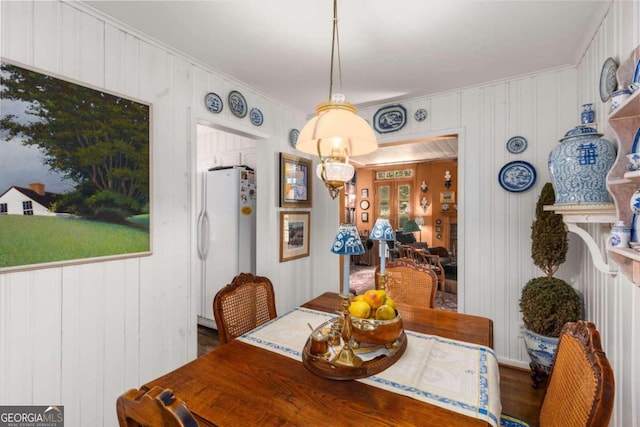 dining area with wood walls, ornamental molding, and hardwood / wood-style floors