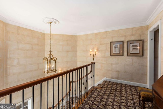 hall featuring ornamental molding, a chandelier, and tile walls