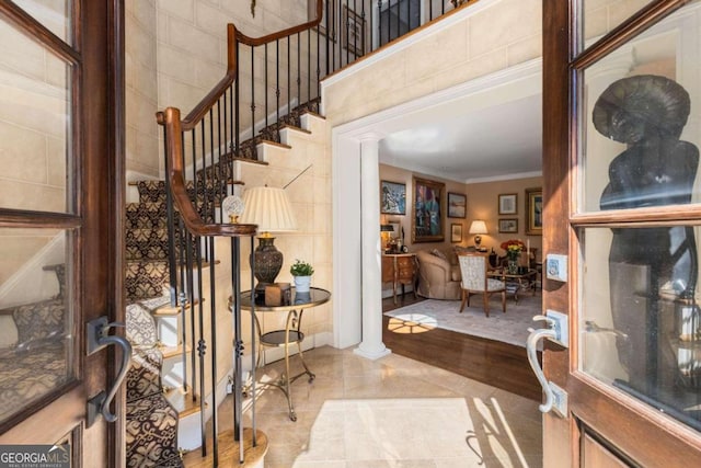 entrance foyer featuring crown molding, decorative columns, and light hardwood / wood-style flooring