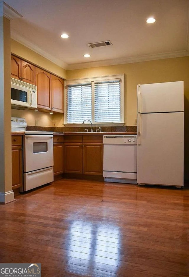 kitchen with white appliances, dark wood-type flooring, ornamental molding, and sink