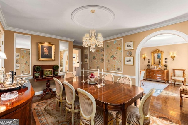 dining area with ornamental molding, wood-type flooring, and an inviting chandelier