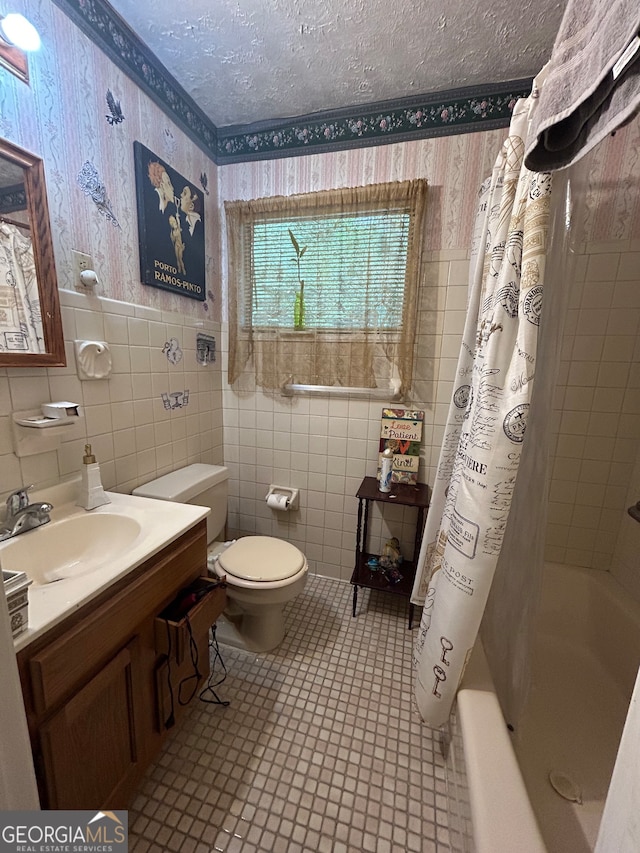 full bathroom featuring toilet, shower / bath combination with curtain, vanity, tile walls, and a textured ceiling