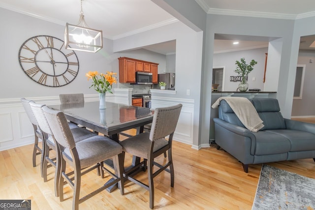 dining space with crown molding, light hardwood / wood-style flooring, and a chandelier