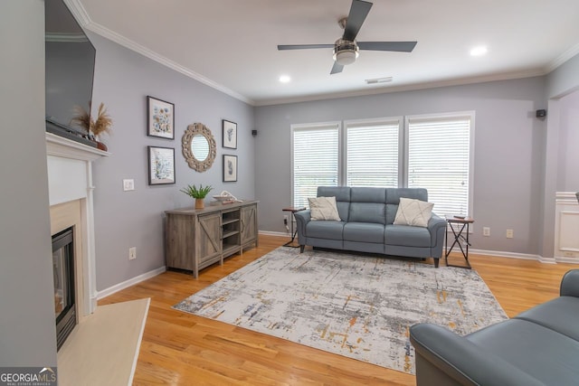 living room with crown molding, light wood-type flooring, and ceiling fan