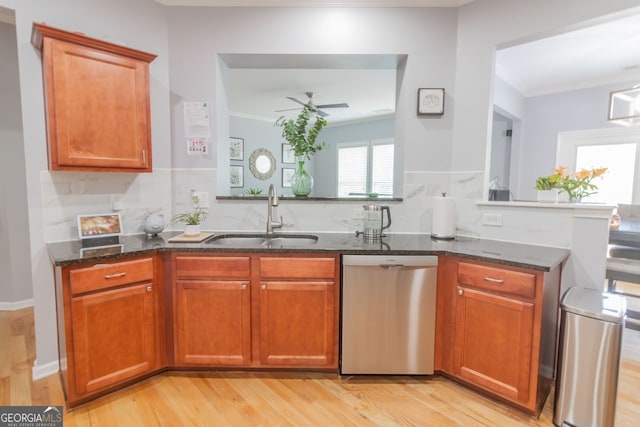 kitchen featuring dishwasher, light hardwood / wood-style flooring, dark stone counters, sink, and crown molding