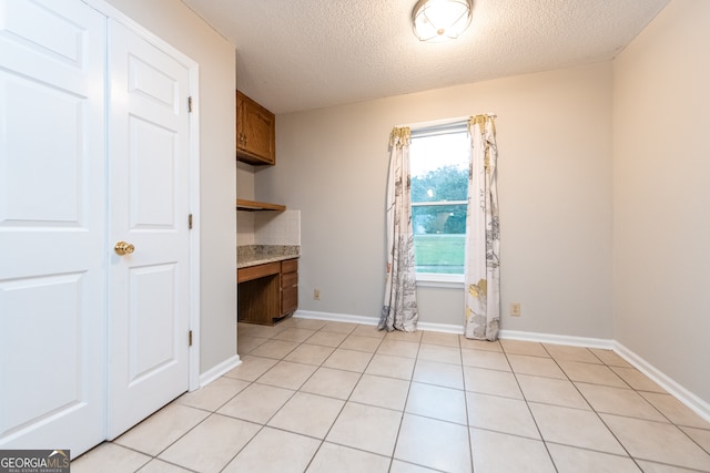 interior space with light tile patterned floors, built in desk, and a textured ceiling