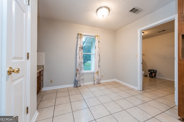 spare room featuring light tile patterned floors and a textured ceiling