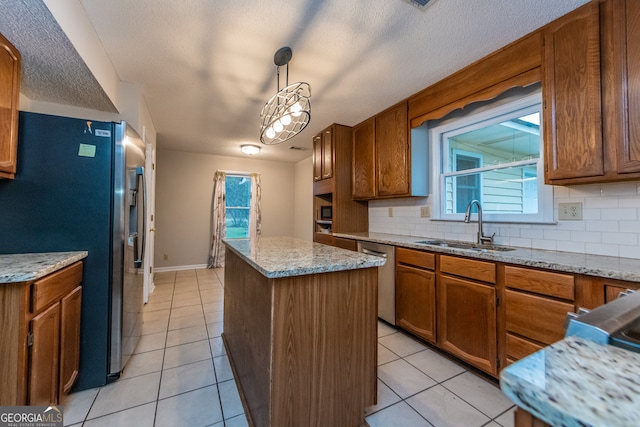 kitchen featuring pendant lighting, a center island, sink, appliances with stainless steel finishes, and tasteful backsplash