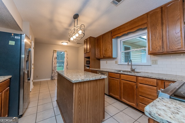 kitchen with appliances with stainless steel finishes, tasteful backsplash, sink, pendant lighting, and a center island