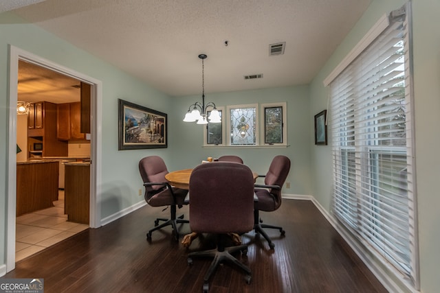 dining space featuring hardwood / wood-style floors, a textured ceiling, and an inviting chandelier