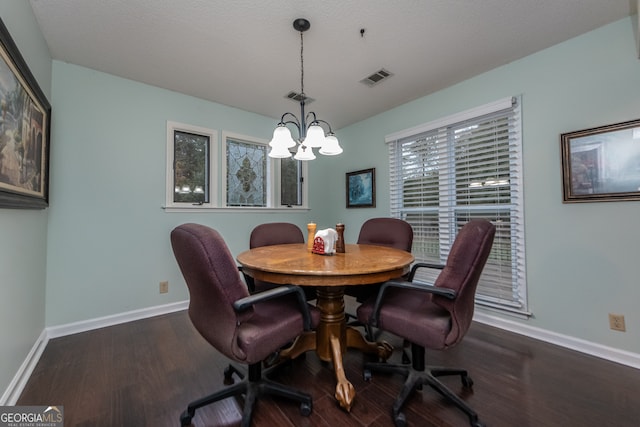 dining area featuring a textured ceiling, dark wood-type flooring, and a notable chandelier