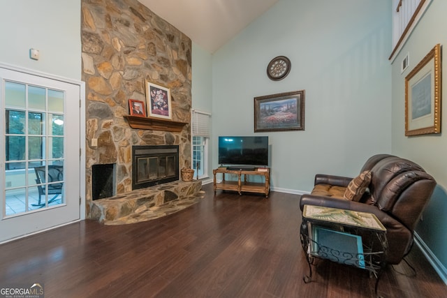 living room featuring dark hardwood / wood-style flooring, high vaulted ceiling, and a stone fireplace