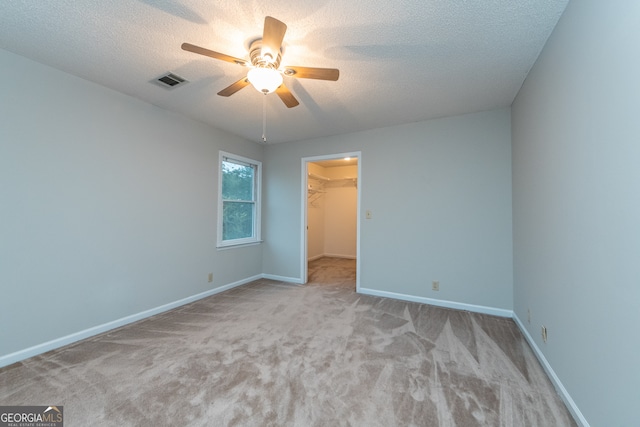 carpeted empty room with ceiling fan and a textured ceiling