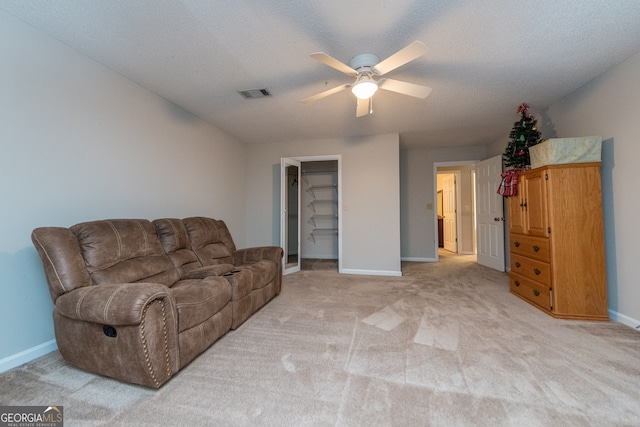 living room featuring ceiling fan, light carpet, and a textured ceiling